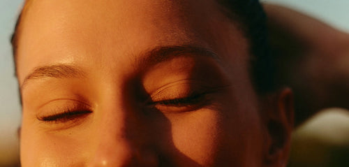 Close up of a woman's closed eyes and skin in sunset light
