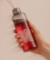 Hand holding a Milamend shaker bottle filled with red drink
