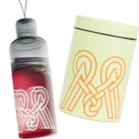 Clear water bottle with red base and white logo, next to a yellow notepad with orange logo on a white background